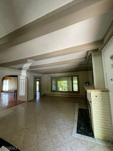 additional living space with beam ceiling, a brick fireplace, and a textured ceiling