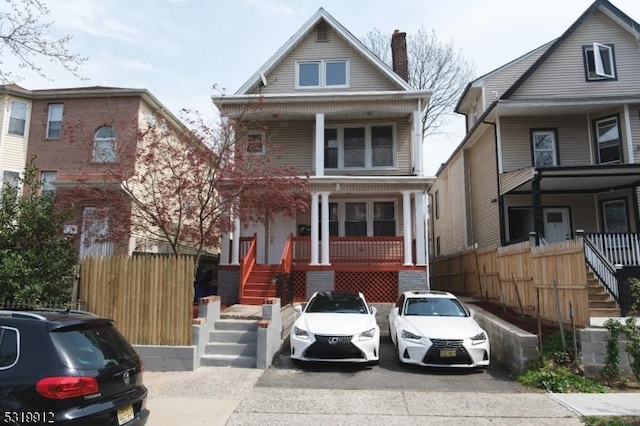 view of front of house with a porch, stairs, and fence