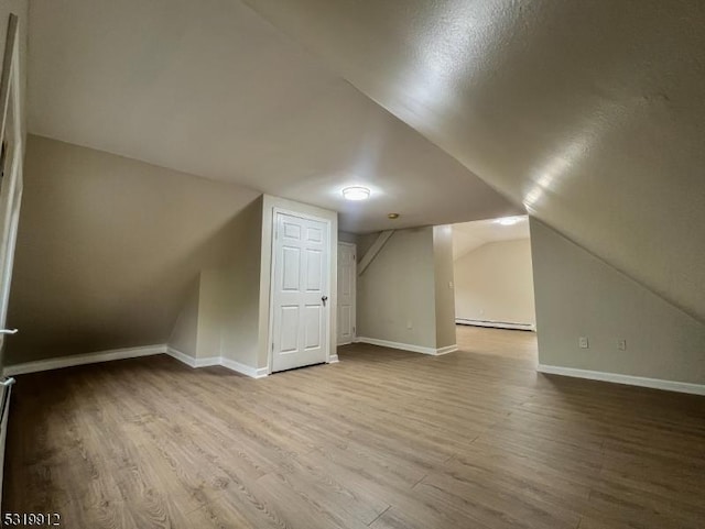 bonus room with baseboard heating, vaulted ceiling, wood finished floors, and baseboards