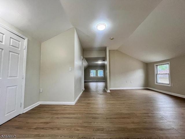 additional living space with lofted ceiling, dark wood-style floors, plenty of natural light, and baseboards