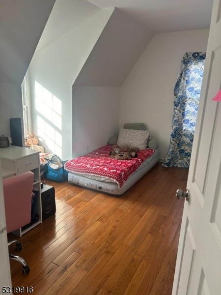 bedroom with wood-type flooring and vaulted ceiling