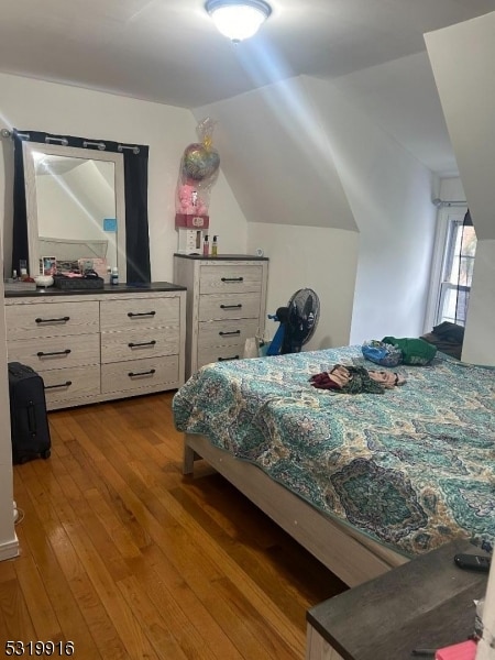 bedroom with vaulted ceiling and hardwood / wood-style flooring