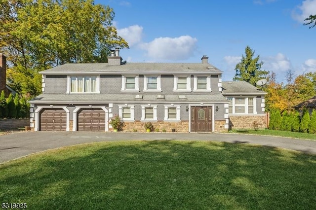 view of front of house with a front lawn, driveway, stone siding, a chimney, and a garage