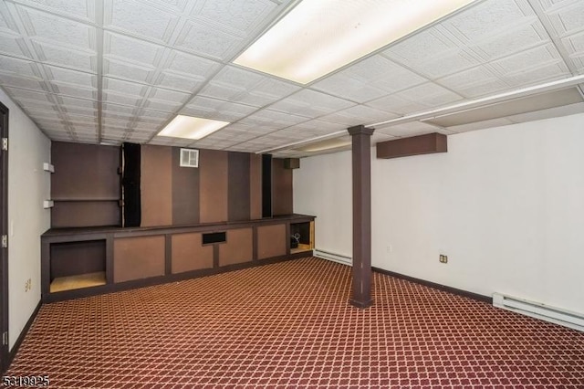 finished basement with a baseboard heating unit, baseboards, visible vents, carpet floors, and a baseboard radiator