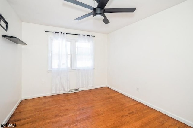 spare room with light wood-style flooring, visible vents, a ceiling fan, and baseboards