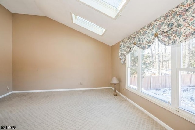 unfurnished room featuring lofted ceiling with skylight, baseboards, and carpet