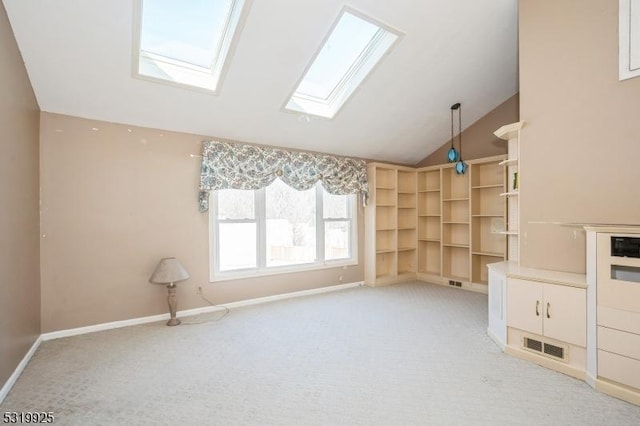 unfurnished living room featuring baseboards, lofted ceiling with skylight, visible vents, and light colored carpet
