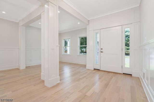 entryway featuring a wealth of natural light, ornamental molding, and light hardwood / wood-style flooring