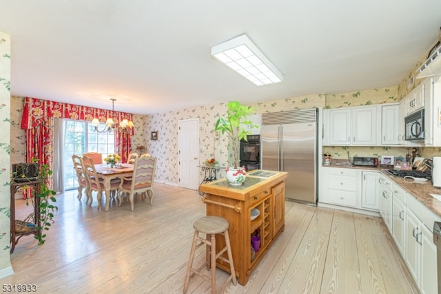 kitchen with a chandelier, black appliances, white cabinetry, and light wood-type flooring