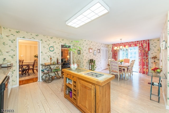 kitchen with a notable chandelier, light hardwood / wood-style flooring, stainless steel dishwasher, and hanging light fixtures