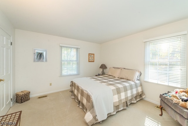 bedroom featuring light carpet and multiple windows