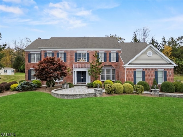 colonial-style house featuring a patio area and a front lawn