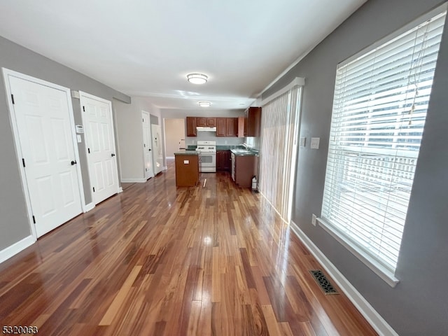 kitchen featuring sink, a kitchen island, white stove, and dark hardwood / wood-style flooring