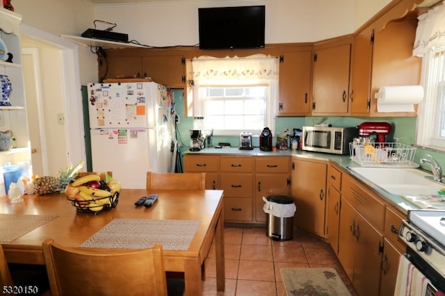 kitchen featuring sink, light tile patterned floors, and white appliances