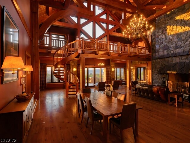 dining room featuring high vaulted ceiling, wood-type flooring, a fireplace, beamed ceiling, and a notable chandelier