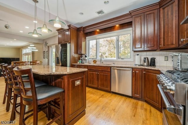20 Crestview Ln, Sparta Twp, NJ 07871 - kitchen featuring appliances with stainless steel finishes, light wood finished floors, a sink, light stone countertops, and a kitchen breakfast bar