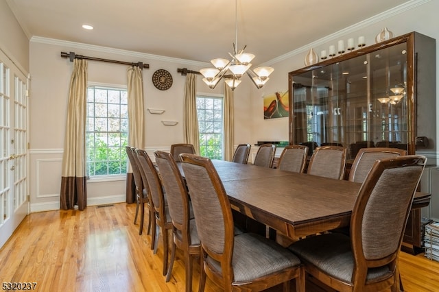 dining space with ornamental molding, a notable chandelier, and light wood-type flooring