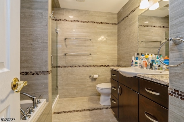 full bathroom featuring tile patterned floors, toilet, tile walls, vanity, and independent shower and bath