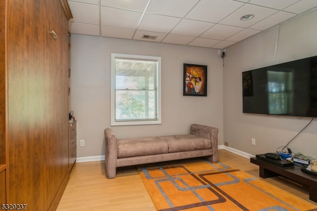 living room featuring a drop ceiling and light wood-type flooring