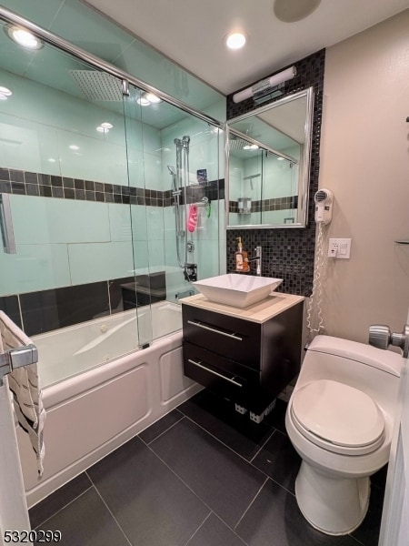 full bathroom featuring toilet, bath / shower combo with glass door, vanity, and tile patterned floors