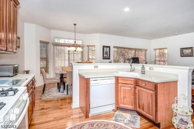 kitchen with a notable chandelier, a healthy amount of sunlight, light wood-type flooring, and white appliances