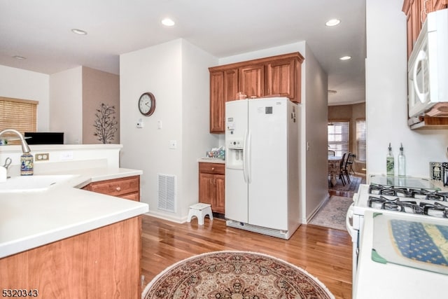 kitchen featuring sink, light wood-type flooring, and white appliances