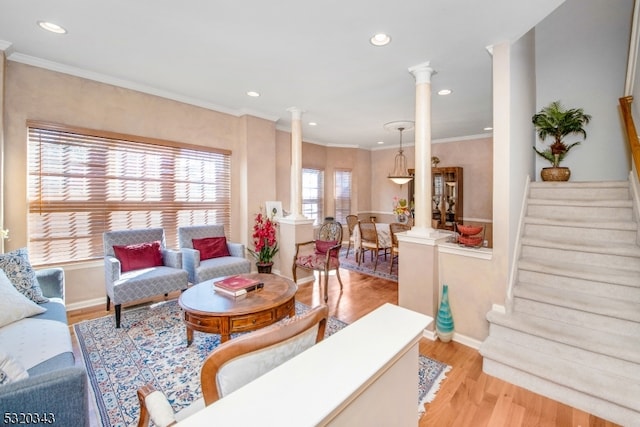 living room with light hardwood / wood-style flooring, ornamental molding, and ornate columns