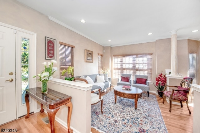 living room with light hardwood / wood-style flooring, crown molding, and decorative columns