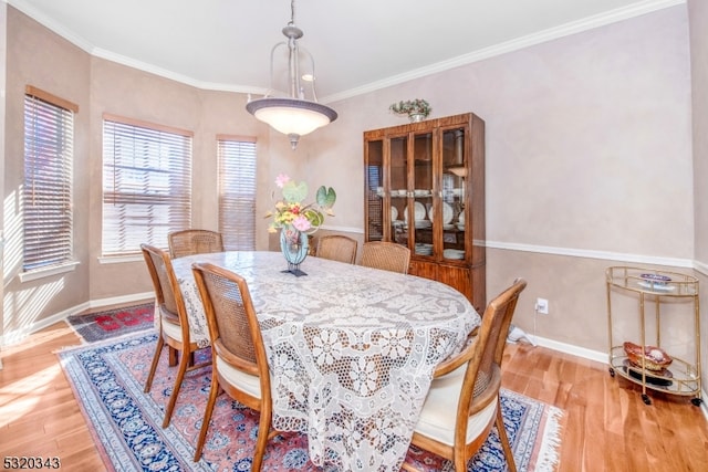 dining room with ornamental molding and light hardwood / wood-style floors