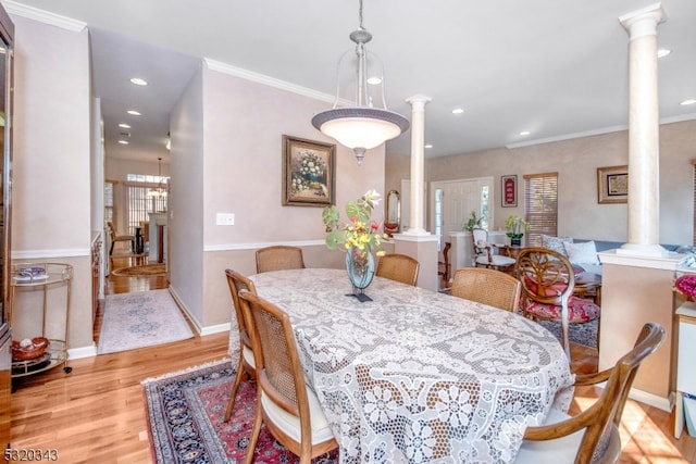 dining space featuring an inviting chandelier, light hardwood / wood-style flooring, ornate columns, and crown molding