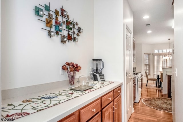 bar featuring a chandelier, light hardwood / wood-style flooring, hanging light fixtures, and gas range gas stove