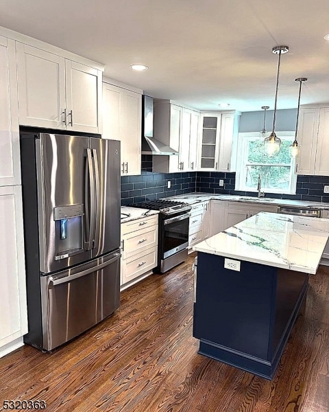 kitchen featuring a kitchen island, appliances with stainless steel finishes, dark hardwood / wood-style floors, pendant lighting, and wall chimney exhaust hood