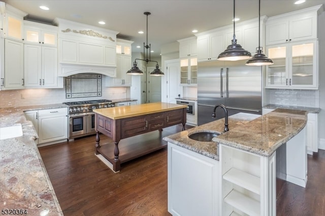 kitchen featuring sink, hanging light fixtures, a kitchen island with sink, white cabinets, and dark wood-type flooring