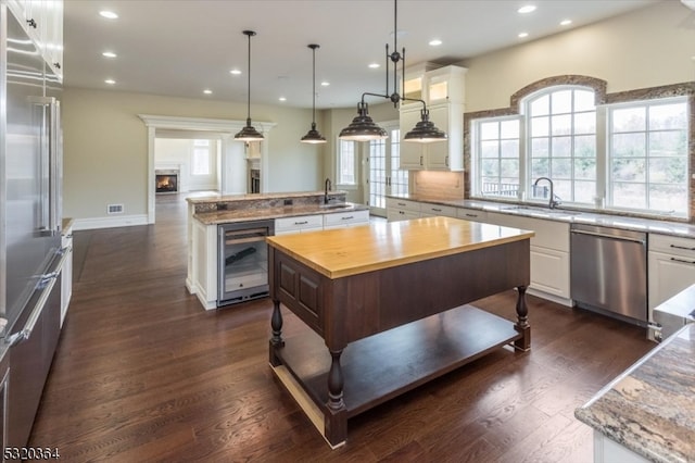 kitchen featuring stainless steel appliances, dark hardwood / wood-style floors, an island with sink, and wine cooler