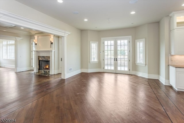 unfurnished living room featuring crown molding, french doors, dark hardwood / wood-style flooring, and a fireplace