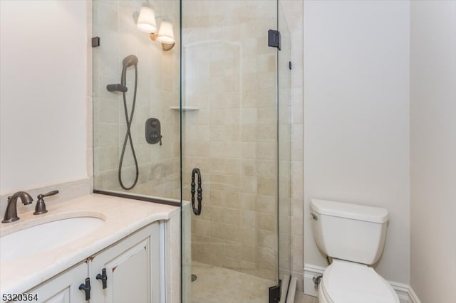 bathroom featuring toilet, vanity, and a shower with door