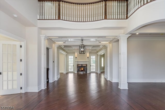 foyer entrance with dark wood-type flooring, a high ceiling, crown molding, and decorative columns