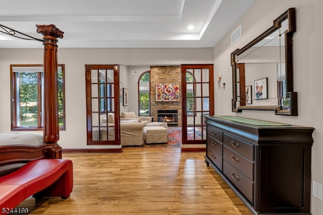 doorway to outside with a fireplace, light hardwood / wood-style floors, and a raised ceiling