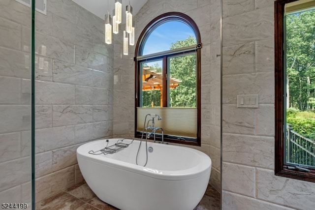 bathroom with a bath, tile walls, and a wealth of natural light