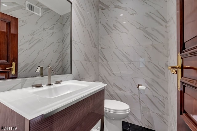 bathroom featuring vanity, toilet, and tile walls