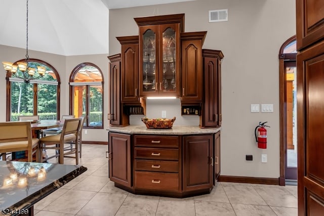 kitchen featuring a notable chandelier, light stone countertops, hanging light fixtures, and light tile patterned floors