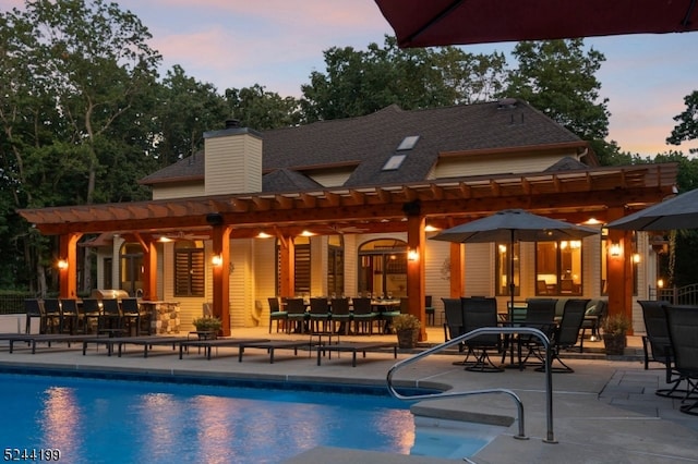 pool at dusk with a patio and a pergola