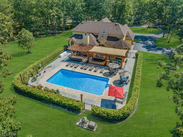 view of swimming pool with an outdoor bar, a patio area, and a lawn