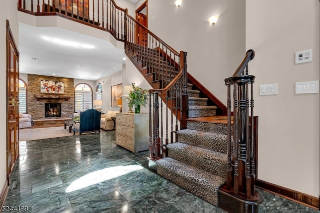 stairway with a towering ceiling and a fireplace