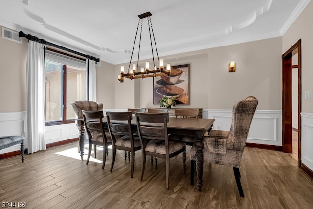 dining room featuring ornamental molding, hardwood / wood-style floors, a barn door, and a notable chandelier