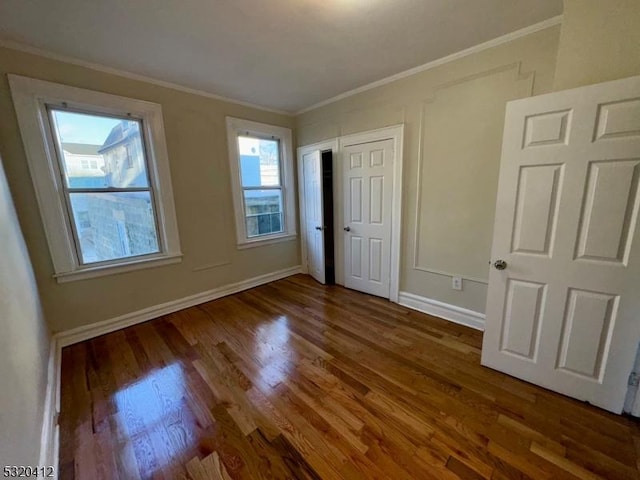 unfurnished bedroom featuring crown molding and dark wood-type flooring