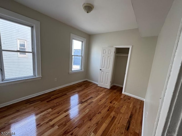 unfurnished bedroom with dark hardwood / wood-style floors and a closet