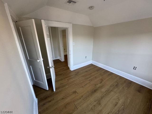 unfurnished room featuring dark hardwood / wood-style flooring and vaulted ceiling