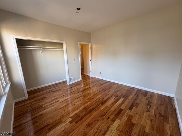 unfurnished bedroom featuring wood-type flooring and a closet