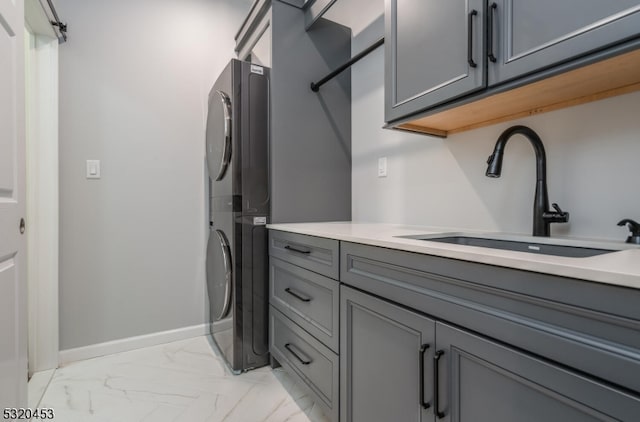 laundry area featuring cabinets, sink, and stacked washer and dryer